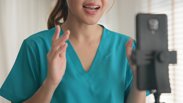 Young adult woman Gen Z asia people anti aging expert modern nurse live talk viral video selfie camera on mobile phone app mental health care. Online sharing digital virtual asian vlogger filming.