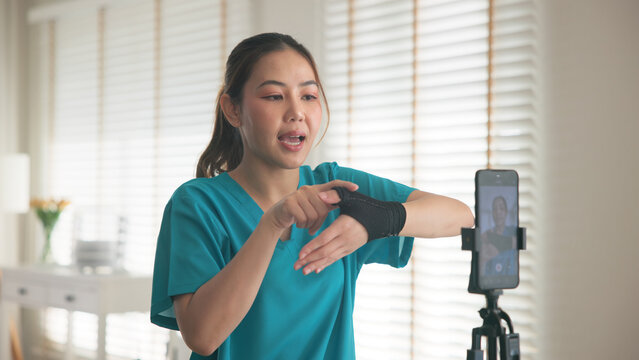 Young adult woman asia people anti aging expert modern nurse live talk video call selfie camera mobile phone app mental health care Online digital virtual asian vlogger filming hand wrist pain physio.