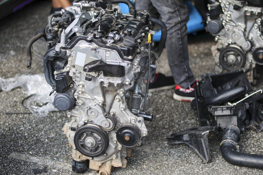 Car engine motor in garage for repair and maintenance. An automotive mechanic works on part, which is ready for rebuild, showing an industrial workshop scene