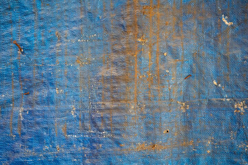 Textured blue and rust-colored weathered tarp surface.
