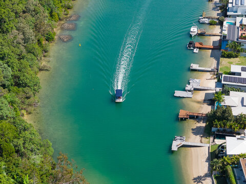 Aerial view of a small boat passing a row of jettys on a coastal canal