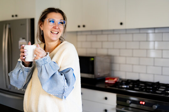 Woman holding a mug while standing in the kitchen