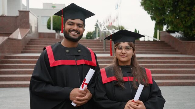 Two Indian graduates holding diplomas smiling happily - Powered by Adobe
