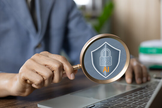Businessman holding magnifying glass focused on AI shield padlock icon. Concept of cybersecurity technology, artificial intelligence data privacy protection, and secure network safety inspection.