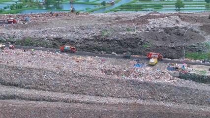 Aerial footage of a landfill in Medan, showcasing heavy machinery managing and organizing waste efficiently - Powered by Adobe