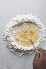 Overhead view of pasta dough being mixed on a white granite countertop, process of making homemade pasta dough
