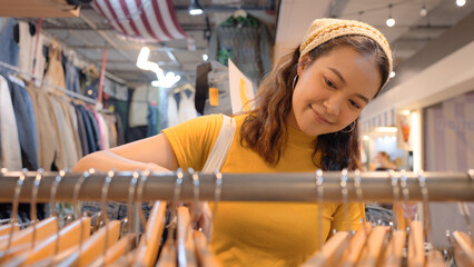 Young teen tourist Gen Z asia female choose look at zero waste eco go green buy second hand sale store flea market thrift old used vintage fabric style. Happy woman city asian people small retail shop