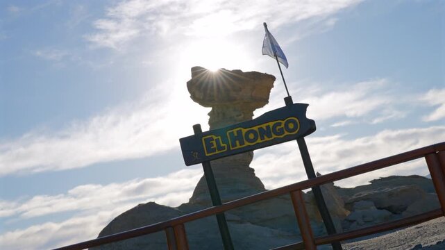 Slow motion drone pan of El Hongo rock formation with sign and sunlight, Valle de la Luna, San Juan.