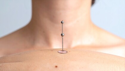 Close up of a navel piercing with a silver barbell jewelry and small pink gem against pale skin in a studio lighting setup