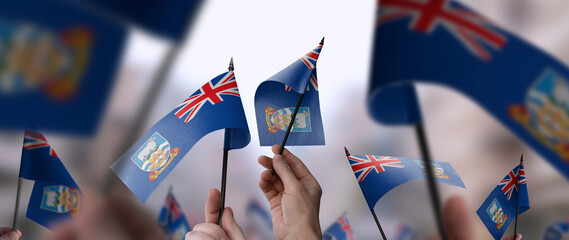 Naklejka premium Falkland Islands flags in their hands on a blurred urban background