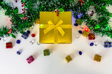 Golden Christmas gift box with green garland and colorful decorations