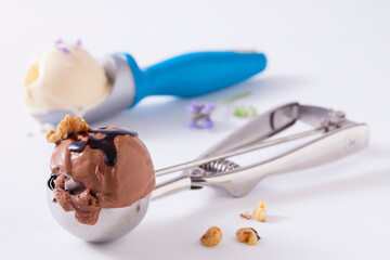 Two ice cream scoopers with chocolate and vanilla ice cream on white. 