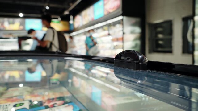 Supermarket Freezer Section with Glass Doors and Shoppers in Grocery Store Aisle