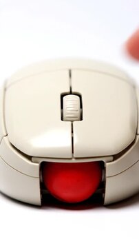 Close Up View of Beige Trackball Mouse with Red Ball and Finger Action on White Background
