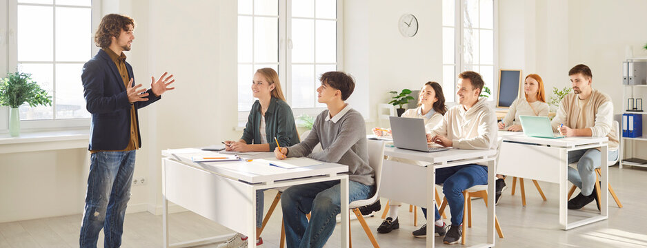 Male teacher leads lesson for group of teenage pupils or students in school classroom, focusing on learning and studying in a supportive setting with dedication and knowledge daily.