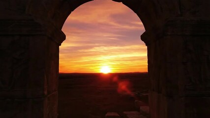 Ancient stone archway frames a vibrant sunset over a vast landscape creating a scene of timeless beauty and historical significance