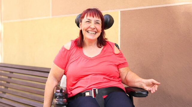 Woman with physical disability smiling in power wheelchair outdoors
