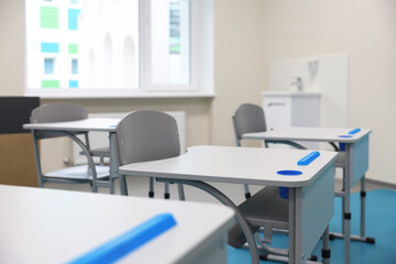 Stylish classroom with desks and chairs at school, closeup