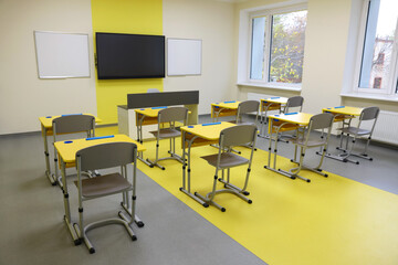 Stylish classroom with desks, chairs and tv at school