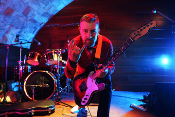 Man with electric guitar showing rock gesture on stage