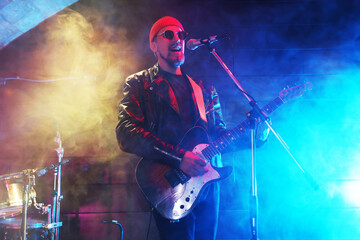 Obraz premium Man playing electric guitar on stage with smoke