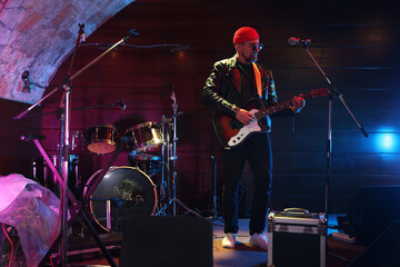 Handsome man playing electric guitar on stage