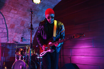Handsome man playing electric guitar on stage
