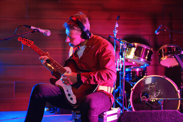Fototapeta premium Man in headphones playing electric guitar on stage