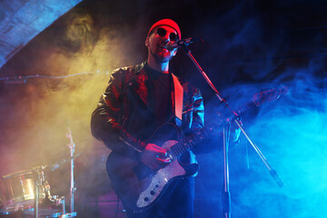 Man playing electric guitar on stage with smoke, low angle view