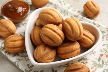 Delicious nut shaped cookies with boiled condensed milk on light table, closeup