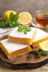 Tasty lemon bars with mint, fresh fruits and tea on wooden table, closeup