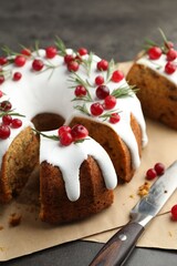 Tasty Christmas cake with cranberries and knife on grey table, closeup