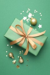 Beautiful Christmas composition with gift and decor on green background, flat lay