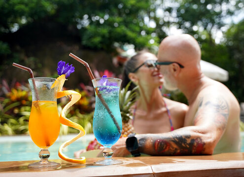 A man and woman with cocktails in a swimming pool