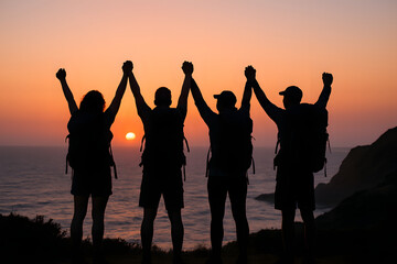 Silhouetted hikers celebrate with arms raised against a stunning sunset ocean backdrop.