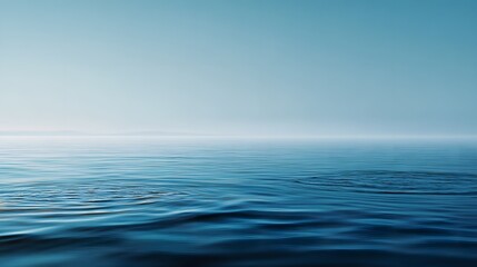 Obraz premium Calm ocean surface displays ripples extending from drops hitting the deep blue water under a pale sky.