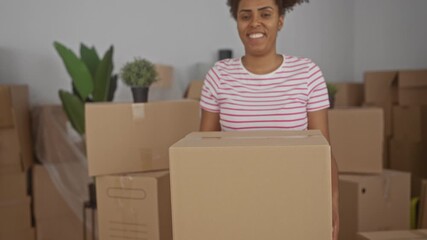 Woman holding a cardboard box with hands inside a building filled with moving boxes; moving day happiness.