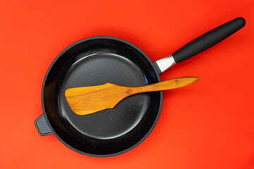 Frying pan with wooden kitchen and copyspace on red background