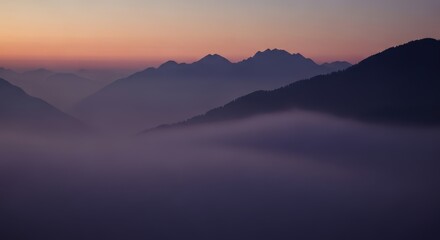 Mountain range silhouettes shrouded in lowlying fog at twilight