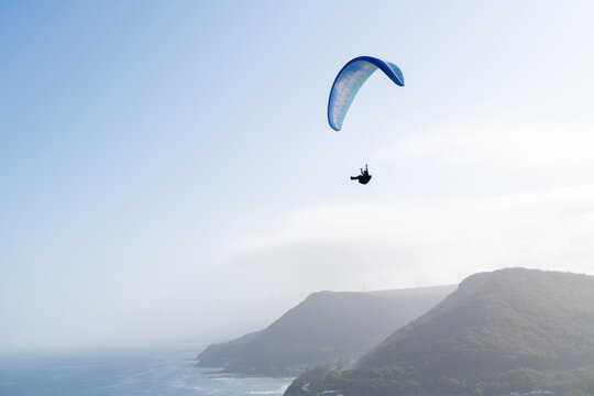 Paragliding against a brilliant sky and coastal mountain range