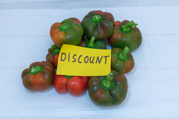 Discount sign on pile of ripe bell peppers