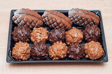 Delicious assortment of chocolate cookies and truffles in a black tray
