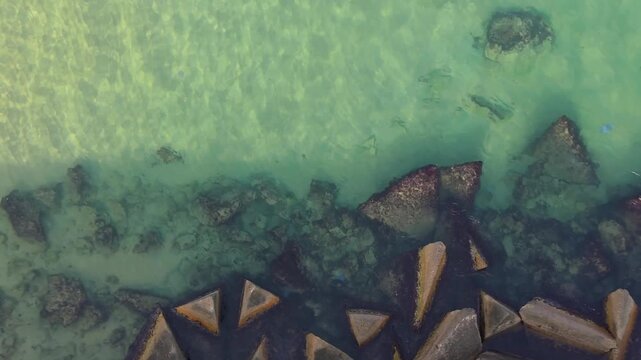 Aerial drone view of clear turquoise sea water over rocky shoreline, transparent ocean surface, underwater stones, calm coastal scenery