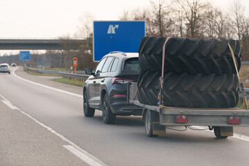Carrying large tractor tires on a trailer traveling on an Autobahn in Germany on an overcast day