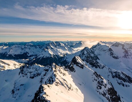 Aerial view of snow-covered mountain range at golden sunrise