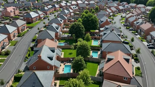 Aerial view of a suburban neighborhood with rows of houses and green trees on a sunny day