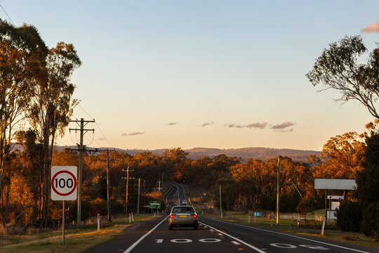 100 speed zone change on country road in Australia with gum trees filling paddocks at sunset