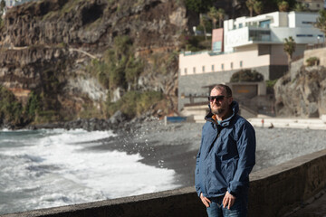 Man stands by the ocean, gazing into the horizon, reflecting on life and searching for deeper...