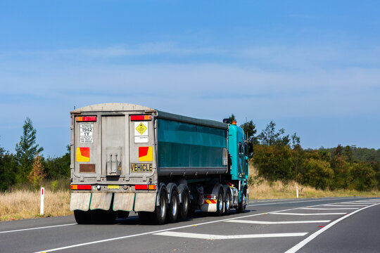 Truck driving down Australian highway with sealed road ahead transporting goods