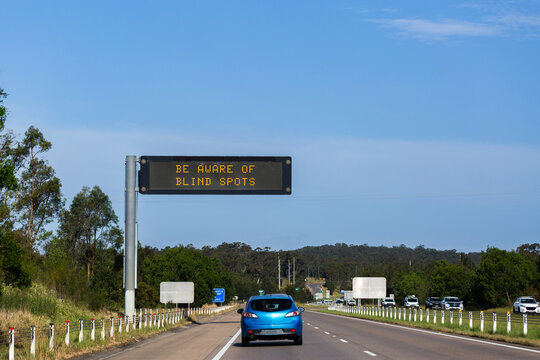 Blue car on the road driving down Australian Highway in with overhead digital sign
